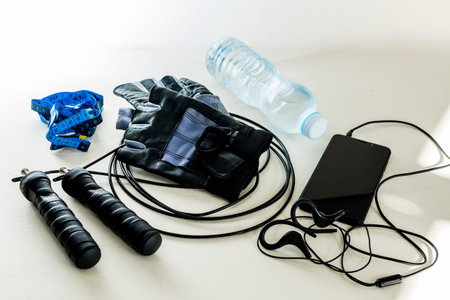 Creative flat lay of physical exercise objects, jump rope, gloves, water bottle, cell phone, centimeter. top view. Concept of diet and healthy living.の写真素材
