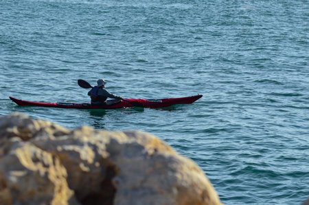 Sunset at the sea in the evening, back light making silhouettes of people doing kayaking and surfing. Gaussian blur.の写真素材