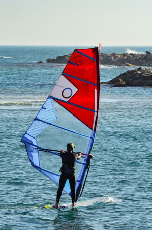 Recreational Water Sports: windsurfer with colored sails in Mediterranean Sea blue water. Tel Aviv beach, Israel. Extreme Sports Action. Healthy Active Lifestyle. Summer Fun Adventure. Hobby.の写真素材