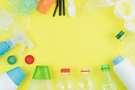 Top view of plastic objects for recycling on a yellow background.