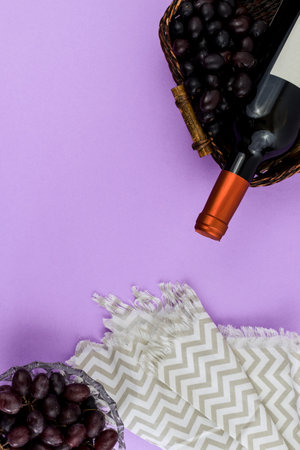 Fresh ripe juicy grapes and bottle of wine on purple violet background. zenith view.の写真素材