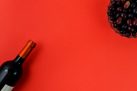 Fresh ripe juicy grapes and bottle of wine on red background. zenith view.の写真素材