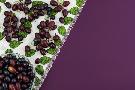 Fresh ripe juicy grapes and bottle of wine on purple violet background, and corks. zenith view.の写真素材