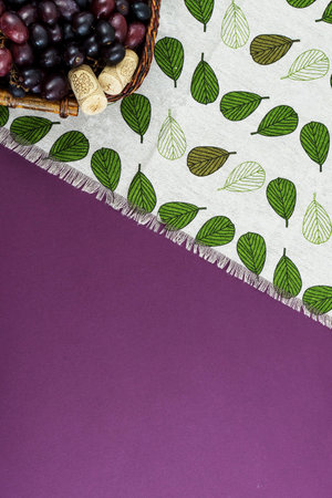 Fresh ripe juicy grapes and bottle of wine on purple violet background, and corks. zenith view.の写真素材