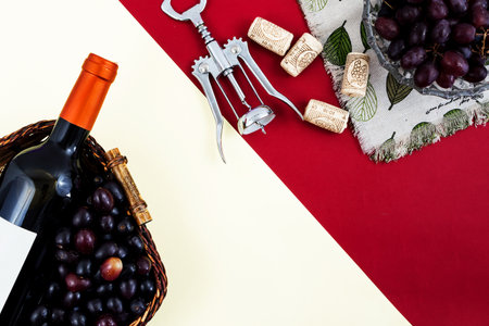 Fresh ripe juicy grapes and bottle of wine on red and yellow background. zenith view. cork and uncover cork.の写真素材
