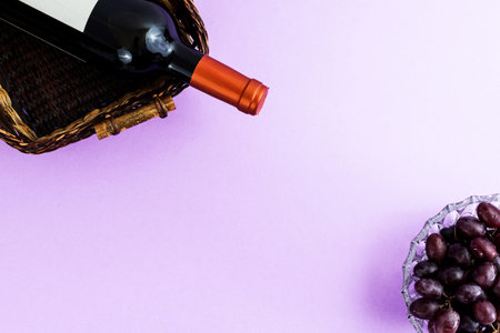 Fresh ripe juicy grapes and bottle of wine on purple violet background. zenith view.の写真素材