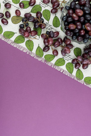 Fresh ripe juicy grapes and bottle of wine on purple violet background, and corks. zenith view.の写真素材
