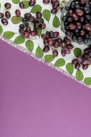 Fresh ripe juicy grapes and bottle of wine on purple violet background, and corks. zenith view.の写真素材