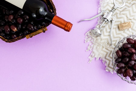 Fresh ripe juicy grapes and bottle of wine on purple violet background. zenith view. cork and uncover cork.の写真素材