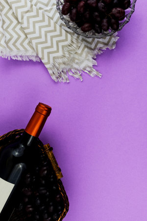 Fresh ripe juicy grapes and bottle of wine on purple violet background. zenith view.の写真素材