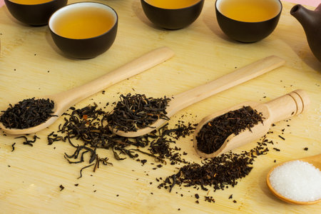 Chinese teapot and cups, wooden spoons with different types of tea herbs, on wooden board. Select focus. Soft focus.の写真素材