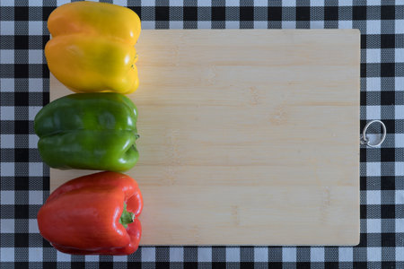 assorted vegetables on wooden board, with knife, on table with black and white checkered tablecloth....