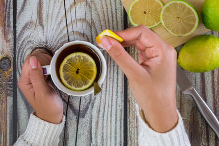 woman hands with cup of tea, on wooden table. top view.の写真素材