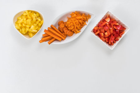 several vegetables, in white saucers. carrots and peppers, on white table. top view