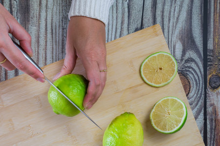 woman hands cutting lemons, on wooden table. top view.