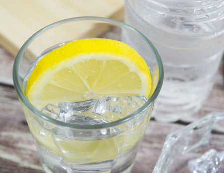 Close up of glass with water and slice of lemon and ice cubes.の写真素材