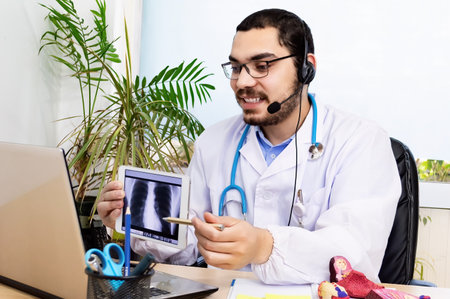 Doctor shows online results to patient x-ray of the lungs. Videoconferencing with patient.の写真素材