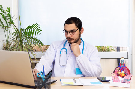 Doctor Pneumologist working with laptop in modern office, and anatomical model of the lung on desk.の写真素材