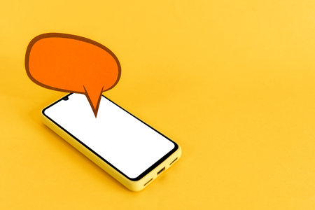 Paper speech bubbles and smart phone with blank screen, on yellow background. Isometric view. Communication and chat concept.の写真素材