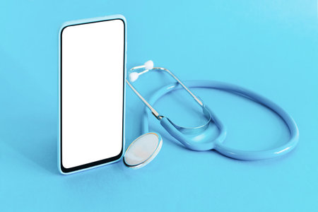 Smart phone and stethoscope on light blue background. Doctor online. Online medical app.の写真素材