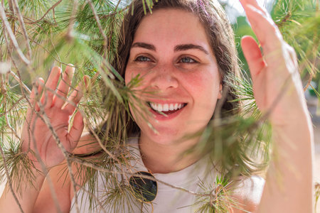 Portrait of a happy young woman among pine tree branches.の写真素材