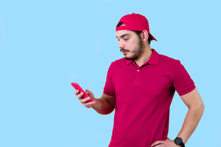 Photo portrait of man keeping mobile phone reading news isolated on light blue color background.