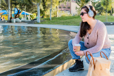 Young woman sitting in park listening to music.の写真素材