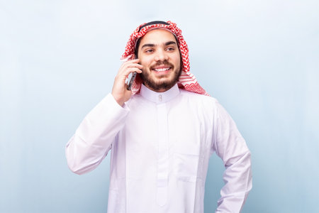 Young arabian, smiling with traditional wear, using the mobile phone.の写真素材