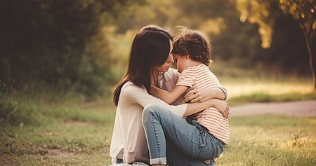 Young brunette mother kneeling hugging her son at park. Generative AI illustration.の素材