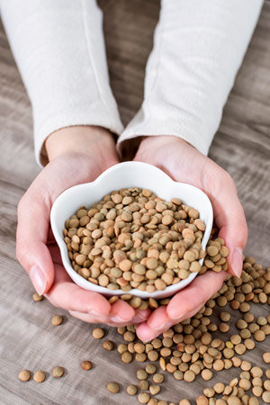 Close-up Of Hands holding bowl with raw lentils.の写真素材