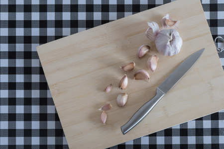 assorted vegetables on wooden board, with knife, on table with black and white checkered tablecloth. garlic,の写真素材