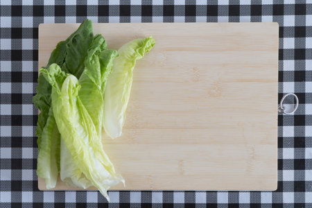 assorted vegetables on wooden board, with knife, on table with black and white checkered tablecloth. lettuce,の写真素材