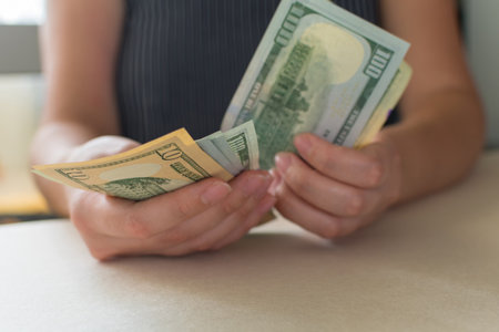Woman's hands counting dollar bills, on white desk. Count money. selective focus.の写真素材