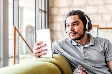 Man reading an e book on tablet sitting on a comfortable couch at home.の写真素材