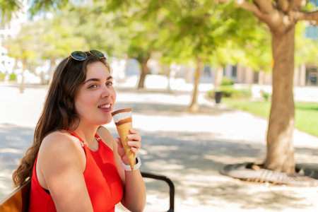 Caucasian women eating ice-cream cone, at park.の写真素材