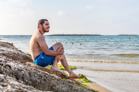 Man sitting on rock enjoying sea view, travel vacations eco tourism outdoor.の写真素材
