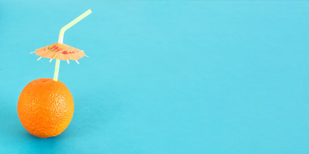 Side view of orange with straw on light blue background.の写真素材