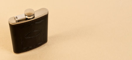 Side view of whiskey flask, hip flask isolated on a beige backgroundの写真素材