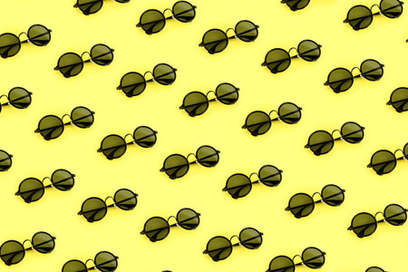 Black sunglasses pattern on pastel yellow background. Minimal summer concept.