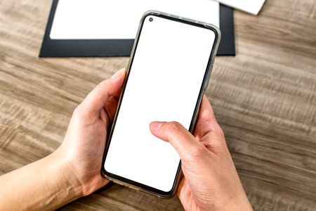 Top view mockup image of a hands holding mobile phone with blank white screen.の写真素材