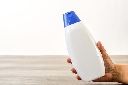 Female hand holding empty shampoo bottle.の写真素材