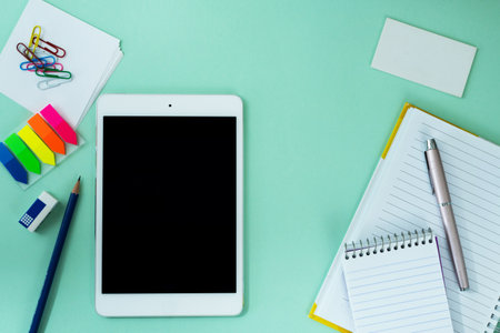 tablet similar to i pad style, with creative office work tools on light blue background, on top view.の写真素材