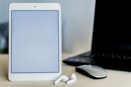 Tablet with blank screen, next to a laptop, on a desk. Technology and business concept.の写真素材