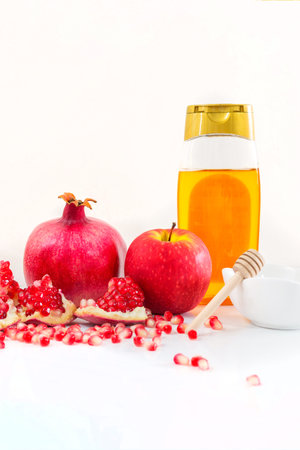 Whole pomegranate, pomegranate seeds, red apple and honey, on white background. Jewish New Year symbols.の写真素材