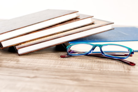 Books and reading glasses on wooden table.の写真素材