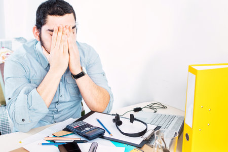 Tired frustrated businessman working from home online. Sitting at home office with laptop during quarantine and self isolation period at pandemic.の写真素材