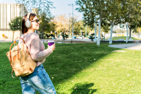 Positive young Woman Enjoying Music Walking Having Coffee Outdoorの写真素材