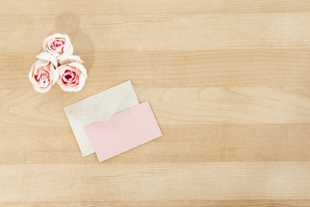Wedding invitation mockup with envelope and flowers, on wooden desk.の写真素材