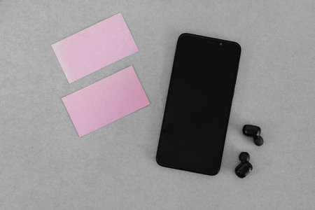 Mock up pink business cards and blank mobile screen on gray table.