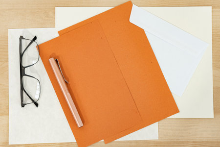 Mock up of orange paper blank with envelope and pen on wooden desk. Autumn Invitation and greetings...
